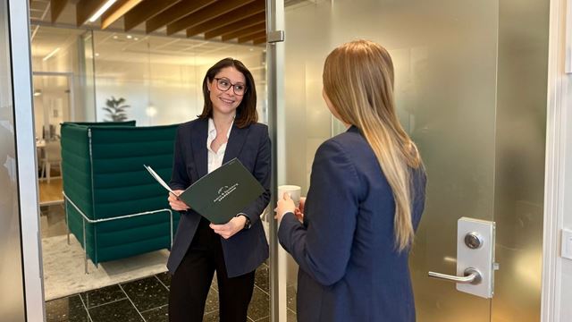 Anniken som holder en folder og ryggen til Ada